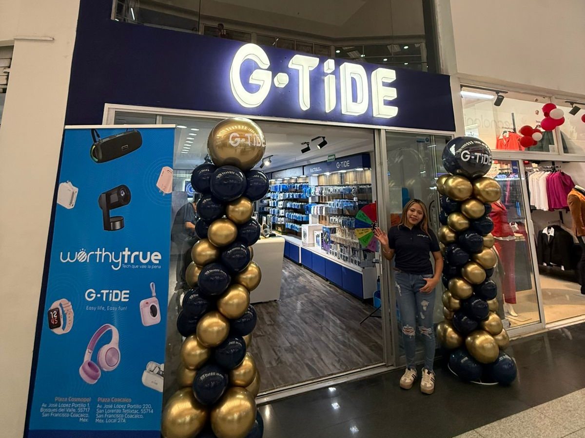 Entrada de la tienda G-TiDE en Plaza Coacalco, con columnas de globos azules y dorados, un anuncio de WORTHYTRUE y una persona que saluda desde la puerta